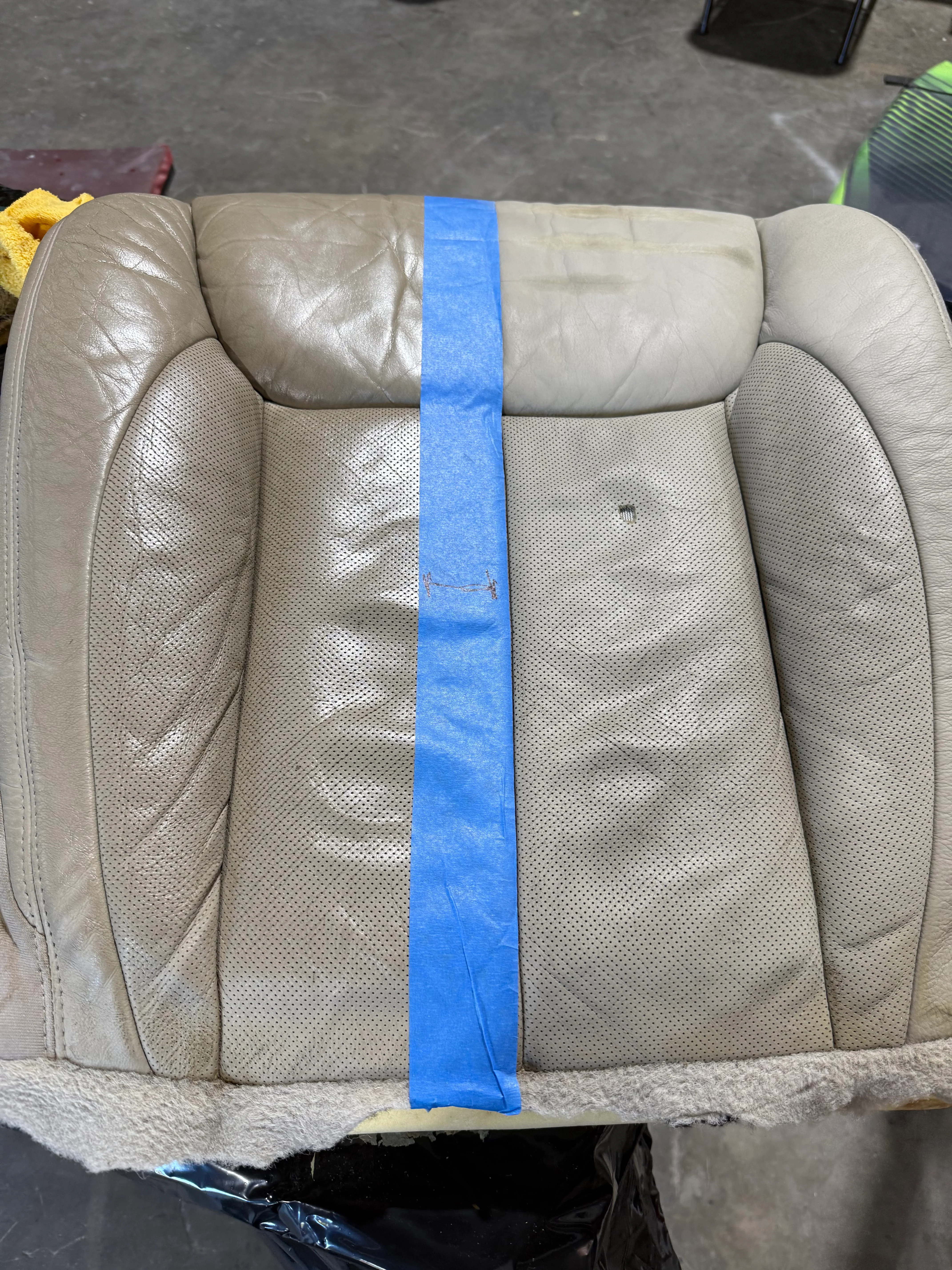 Gray leather seat cushion with blue tape